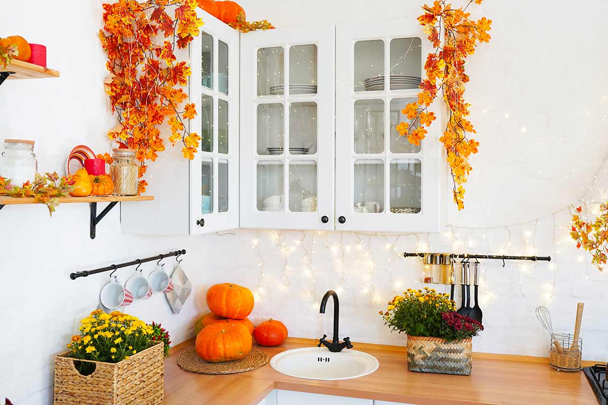 cucina decorata per l'autunno con zucche e catene luminose